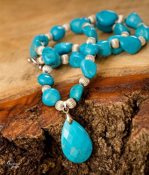 turquoise necklace lying on raw cut of wood